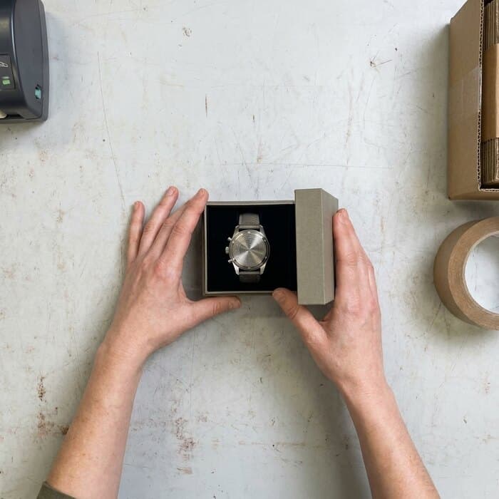 A wristwatch in its open box, caseback turned to the camera