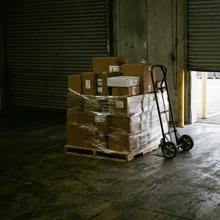 A built pallet waiting at the loading dock beside a hand truck