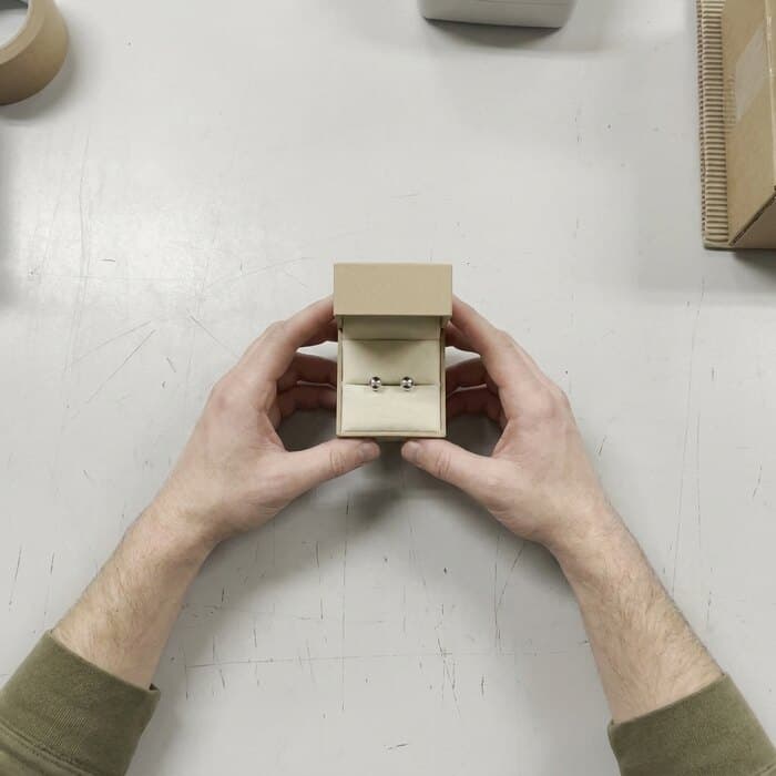 A pair of stud earrings in an open box on the bench
