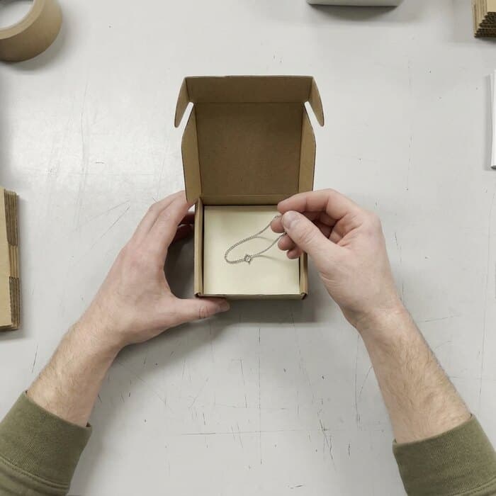 A slim bracelet held above its box before packing