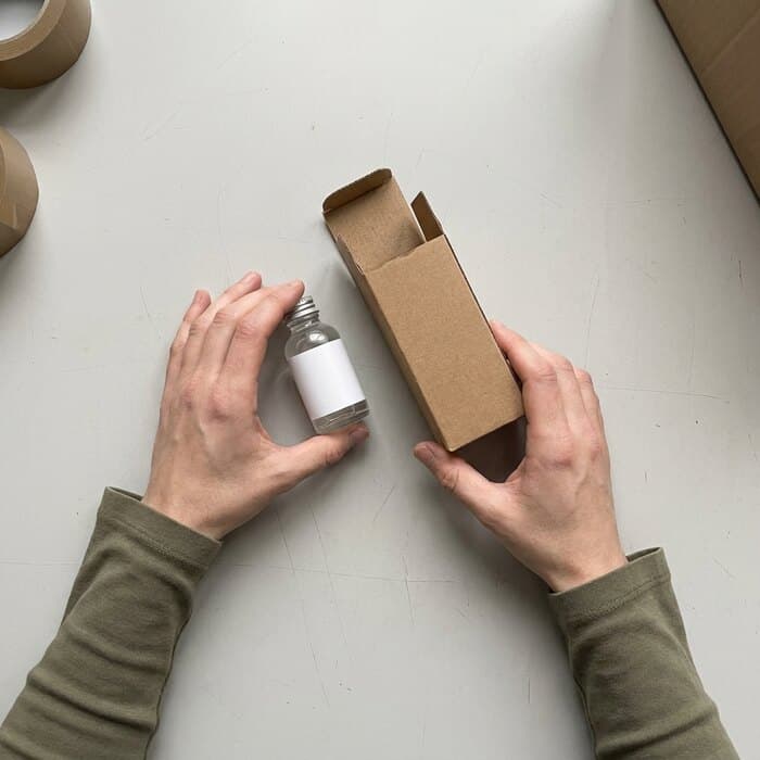 A skincare bottle and its carton on the packing bench
